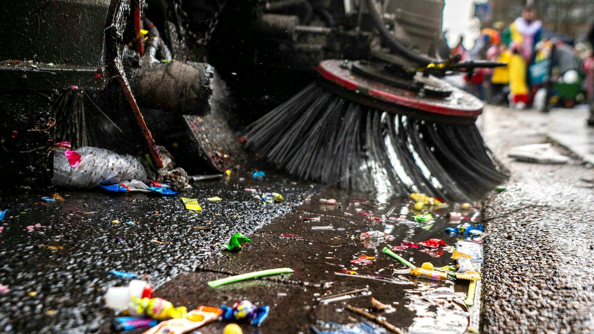 Eine Kehrmaschine sammelt die liegen gebliebenen Kamelle beim Rosenmontagszug in Euskirchen ein.