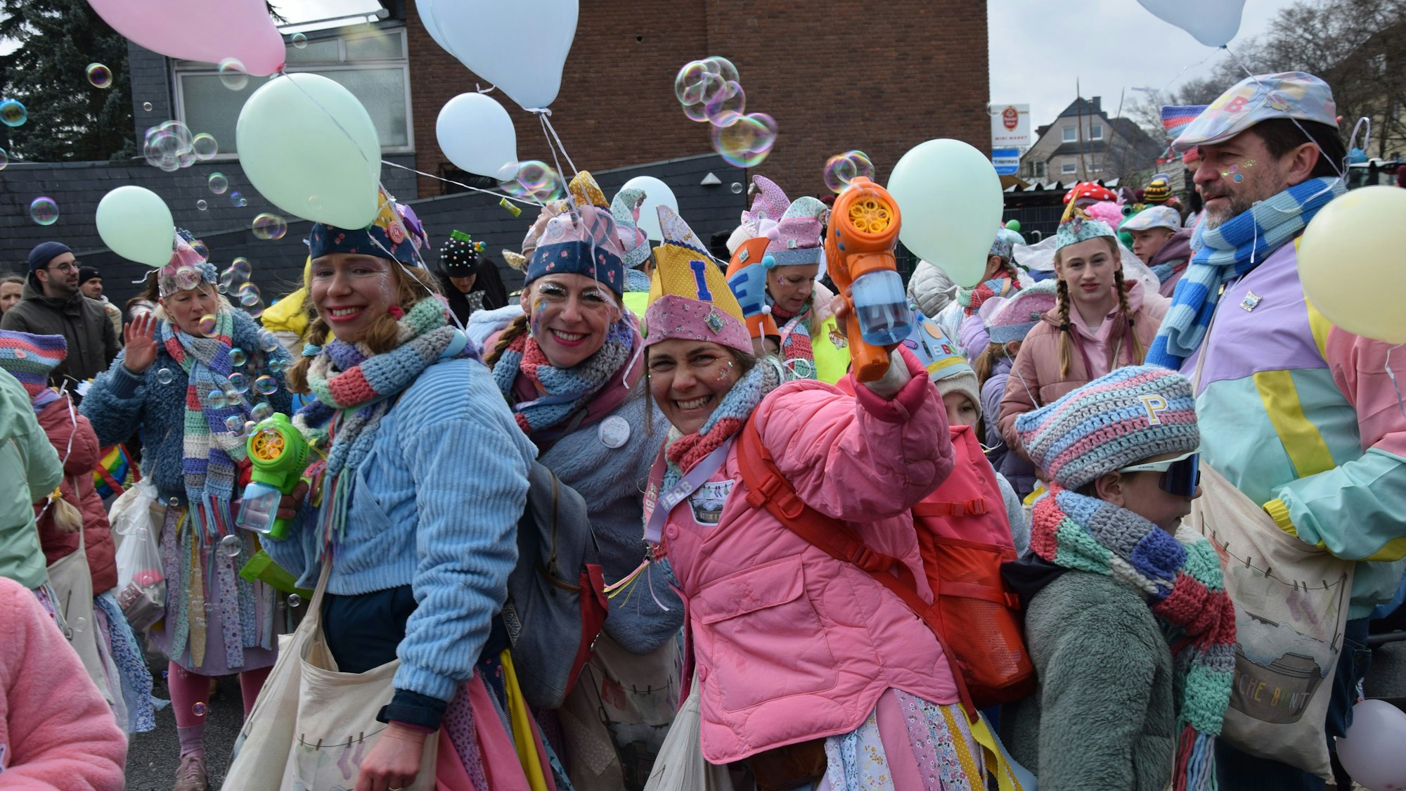 Frauen mit Luftballons an der Kleidung schießen mit Seifenblasen-Pistolen.
