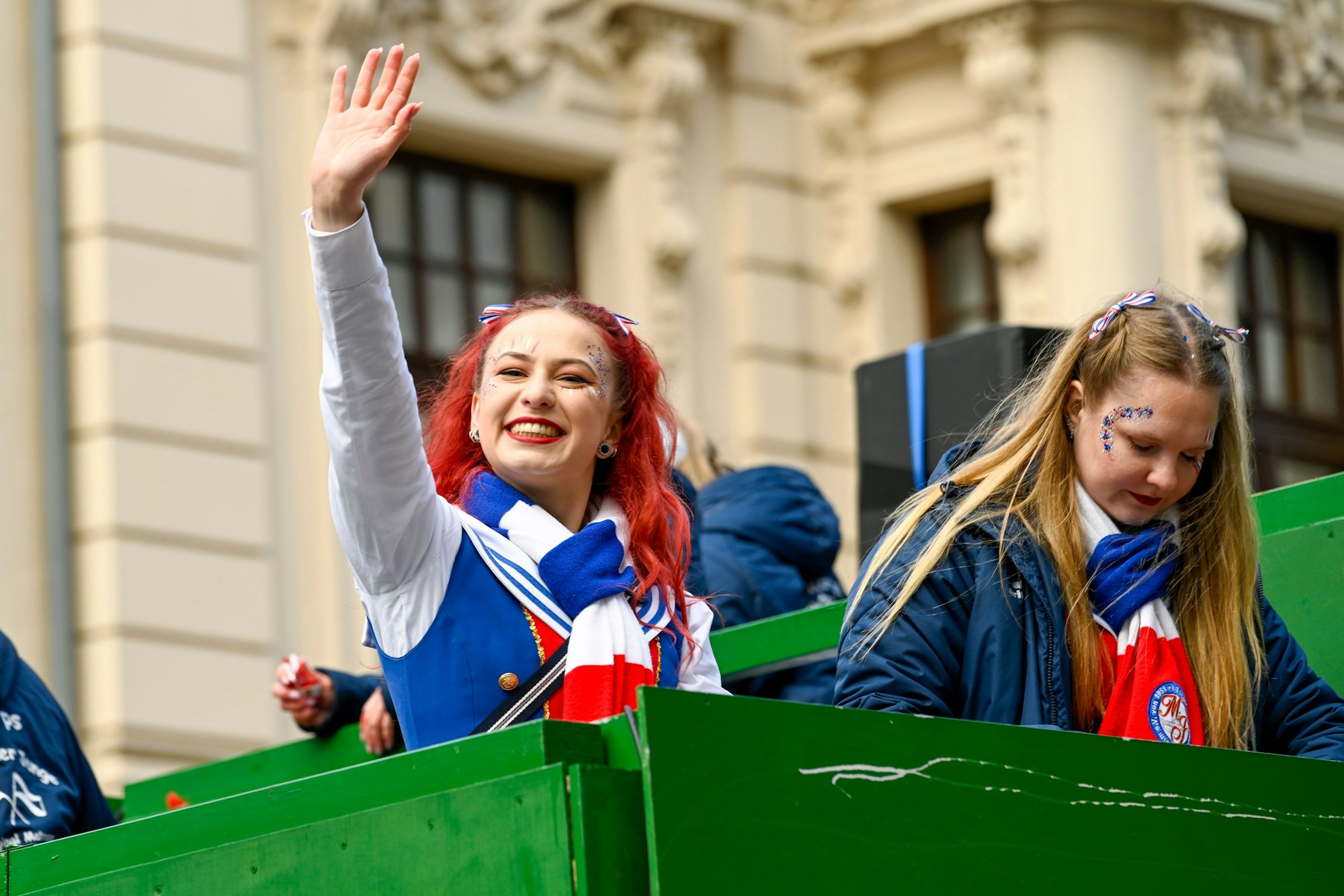 Zwei junge Mädchen fahren auf einem Karnevalswagen mit.