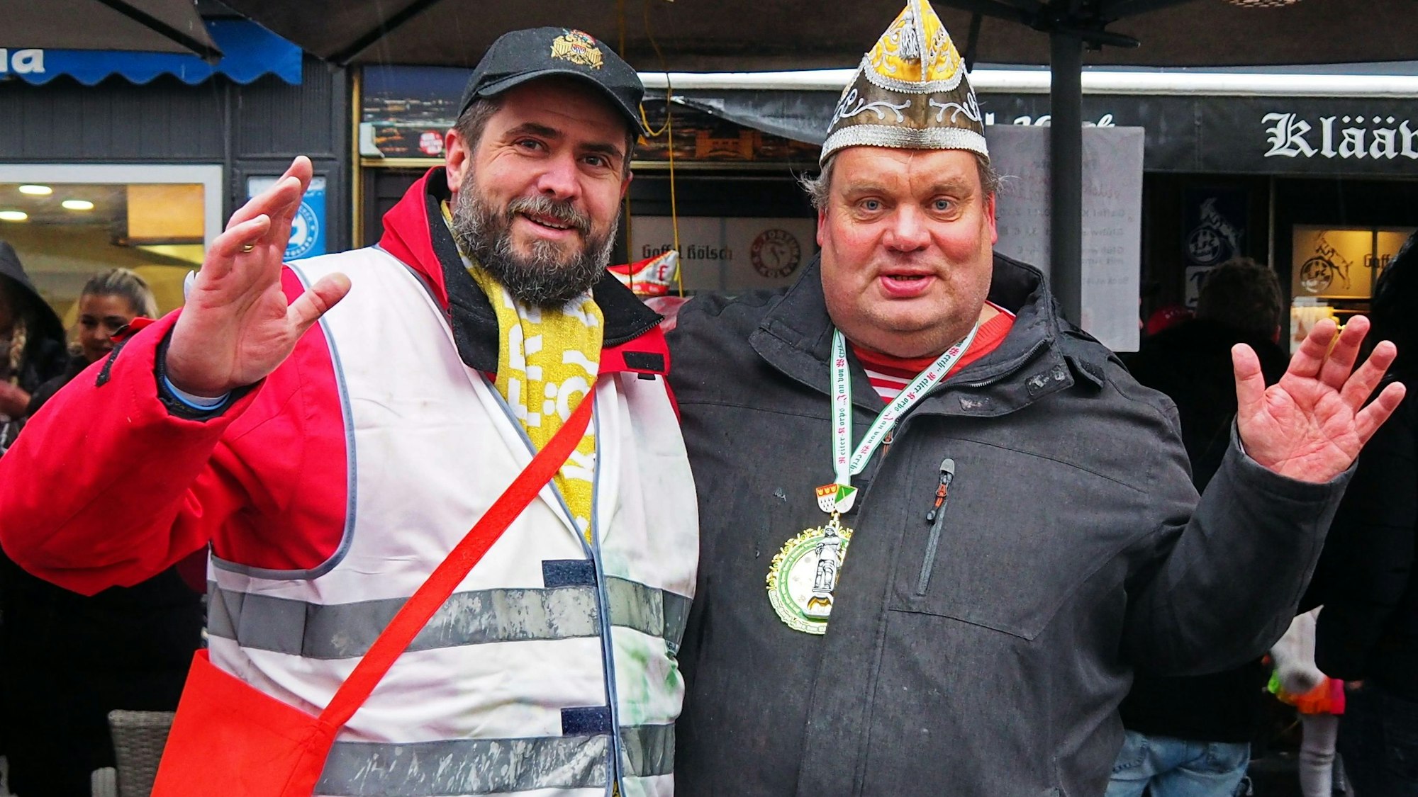 Zwei Männer winken in die Kamera.