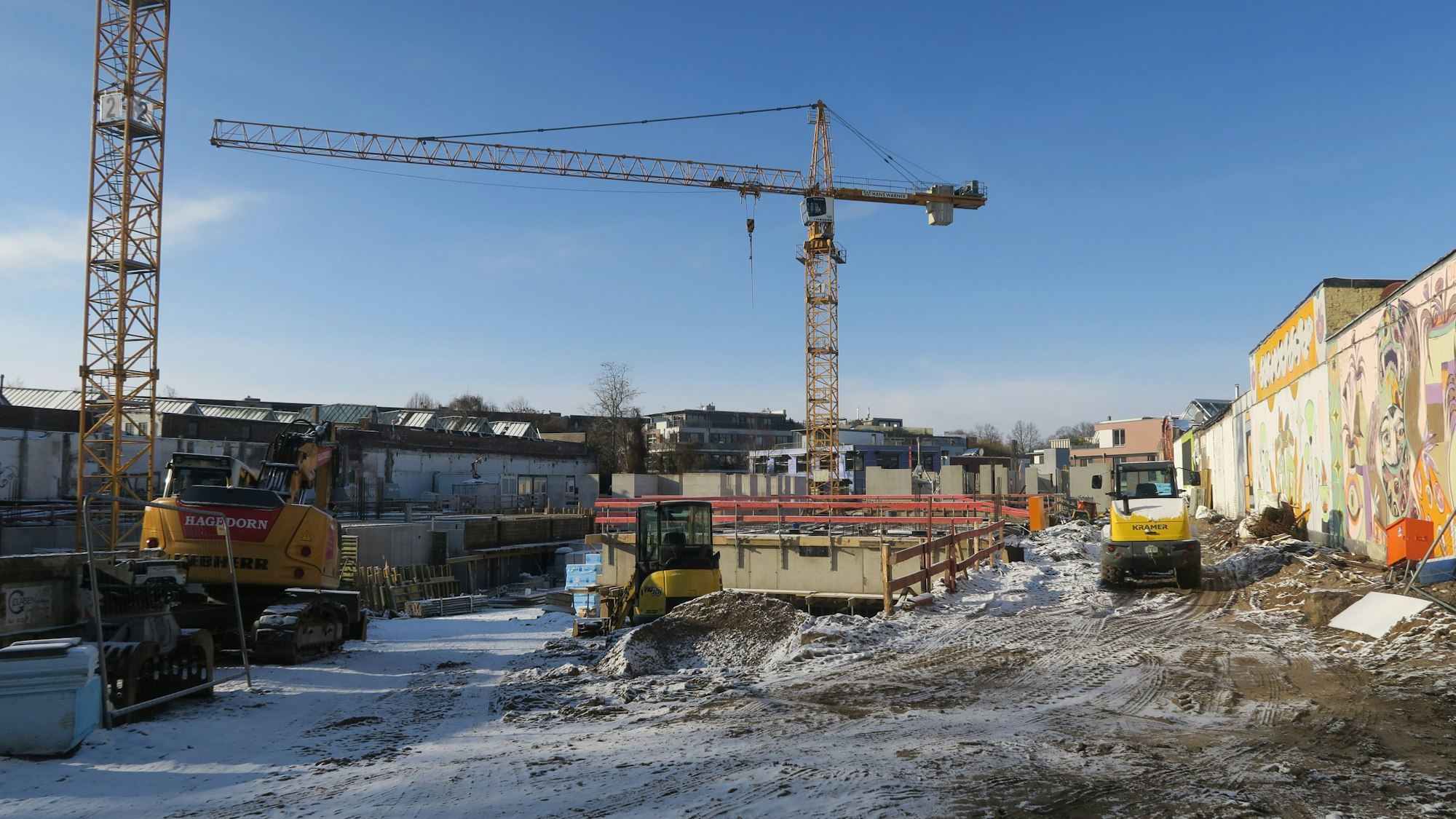 Kräne und anderes Baugerät steht an einer Baustelle, an der Wohnungen entstehen.
