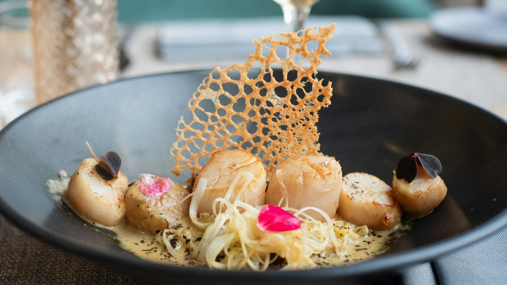 Sechs Nüsse in einer Reihe auf Lauch- und Quinoabett: So richtet Küchenchef Aurelien Leclerc seine Jakobsmuscheln an. Dazu empfiehlt er einen trockenen Weißwein.