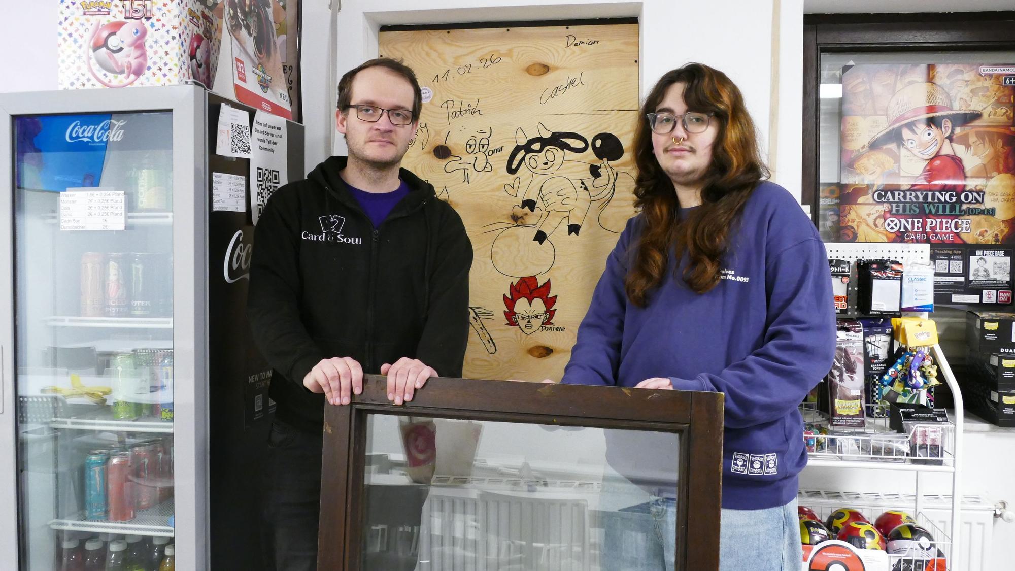 Patrick Overkamp und Castiel Heidenreich, die beiden Inhaber des Card & Soul, stehen vor dem Fenster, das der oder die Einbrecher herausgebrochen hatten.