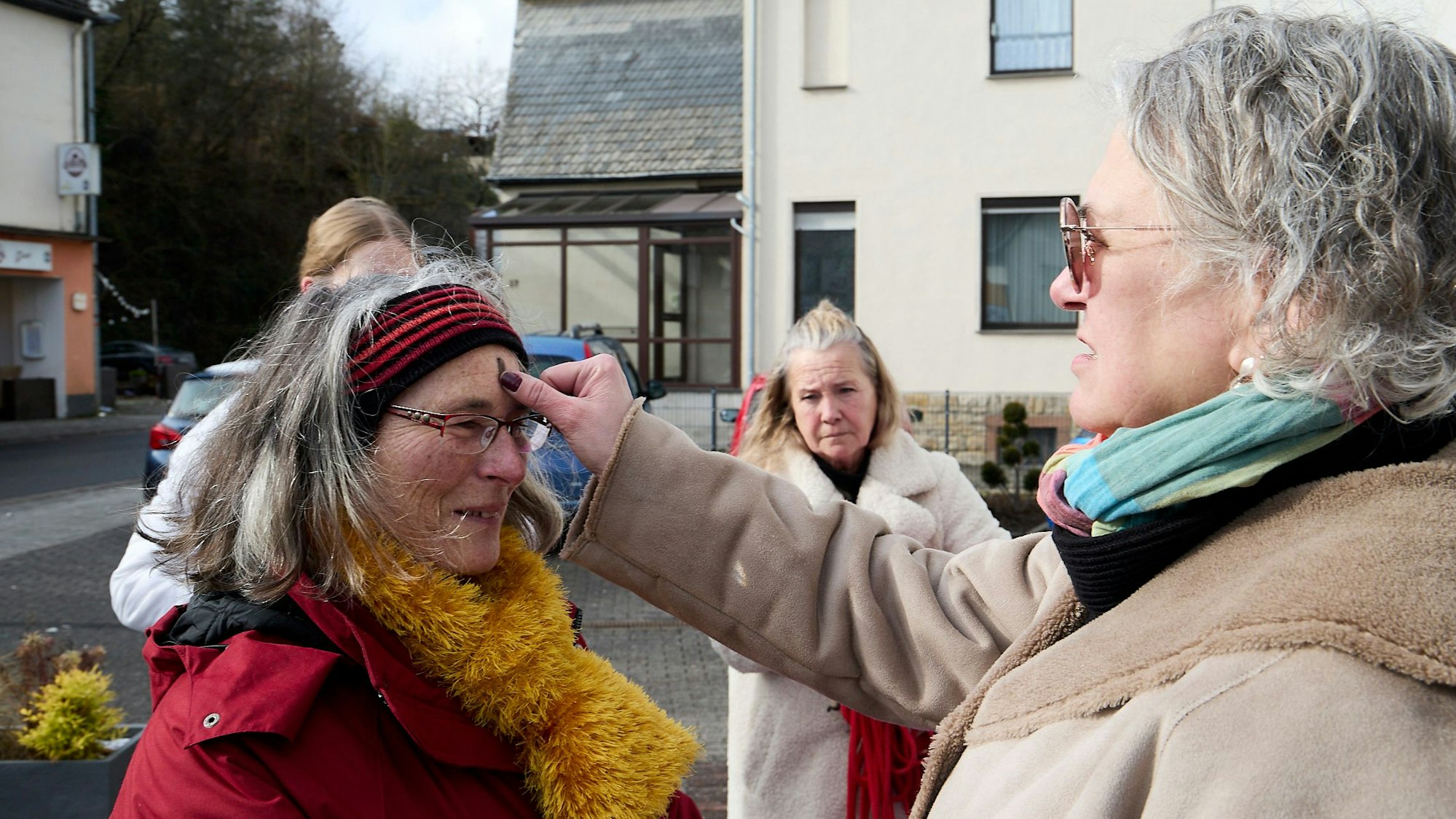 Astrid Sistig zeichnet ein Aschenkreuz auf die Stirn von Monika Hahn.