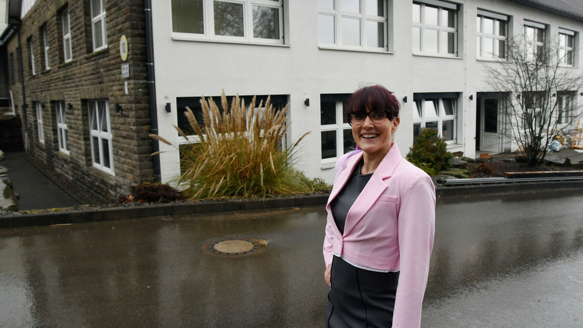 Eine Frau steht vor einem großen Gebäude, in dem demnächst ein Gesundheitszentrum eröffnet wird.