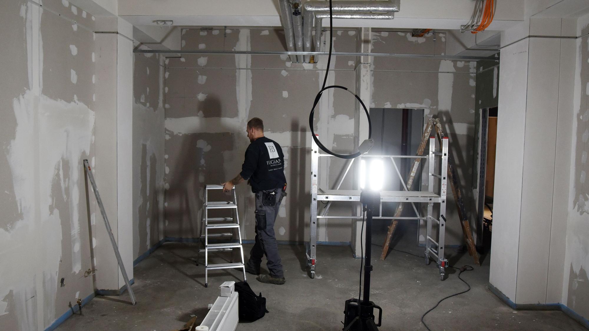 Blick auf einen Raum, in dem ein Handwerker gerade die Lampen montiert.