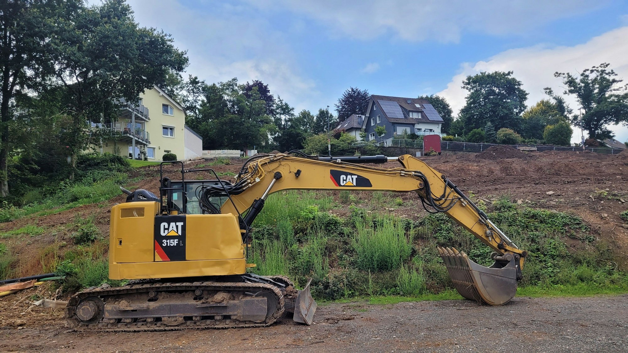 Ein gelber Bagger steht vor einem gerodeten Hang.