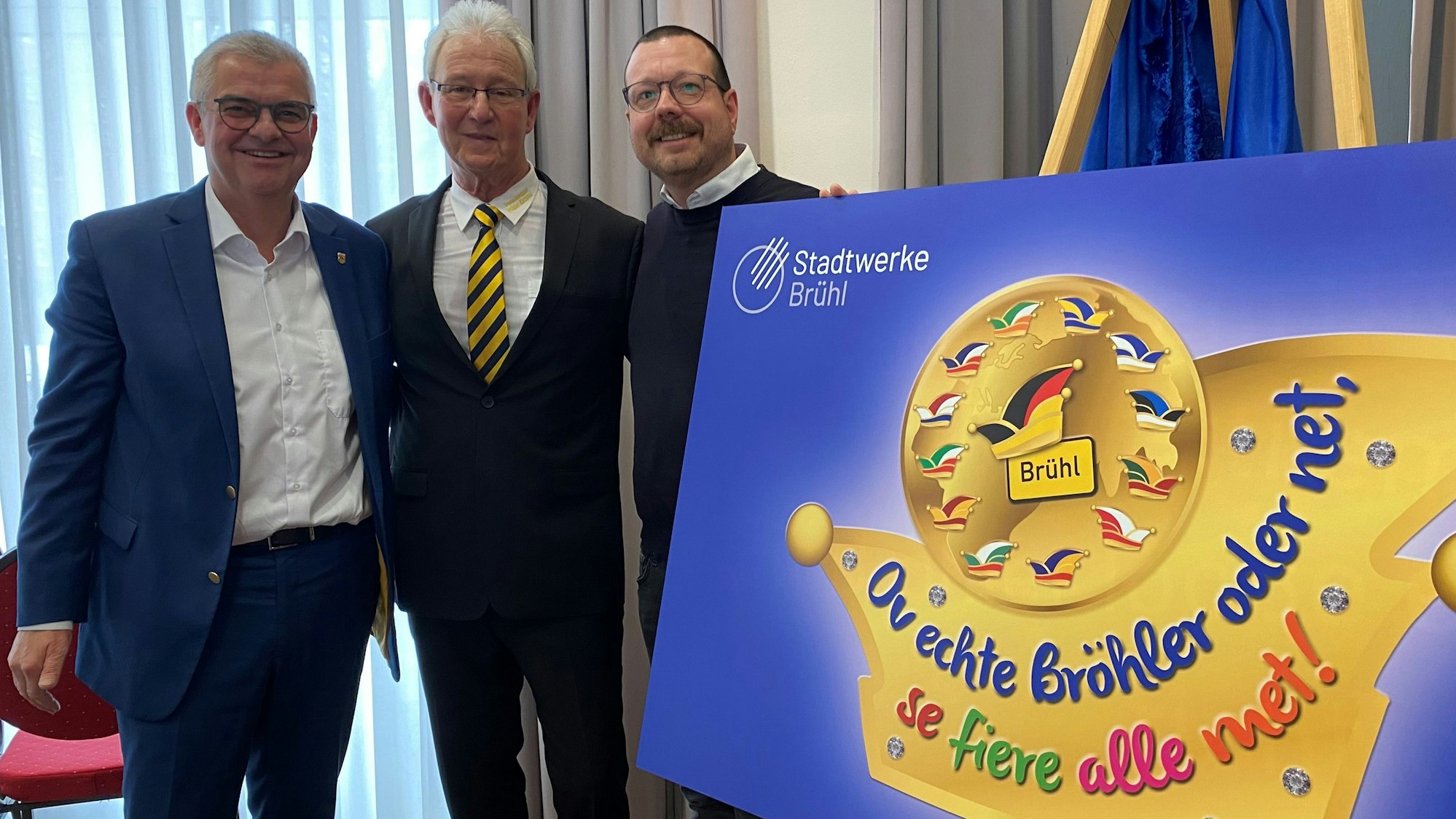 Zu sehen sind Dr. Marc Prokop, Georg Müller und Martin Lösch, sie stehen hinter einem Schild, das das Sessionsmotto zeigt.