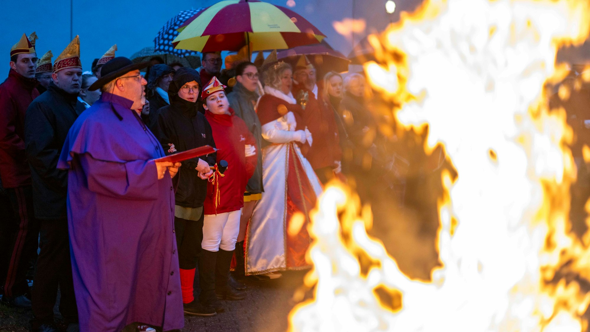 Das Bild zeigt einen Moment während der Nubbelverbrennung. Während die Strohpuppe brennt, schunkeln die Karnevalisten im Hintergrund.