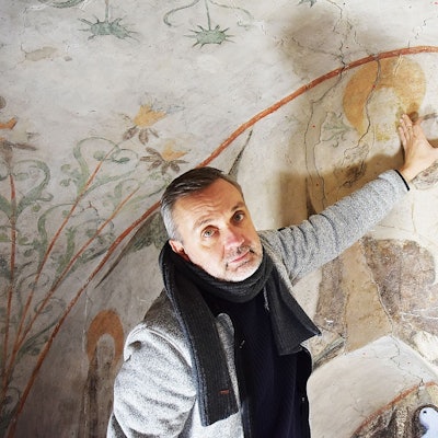 Das Foto zeigt den Restaurator Christian Rubin, der auf eine der kritischen Stellen an der Decke zeigt.