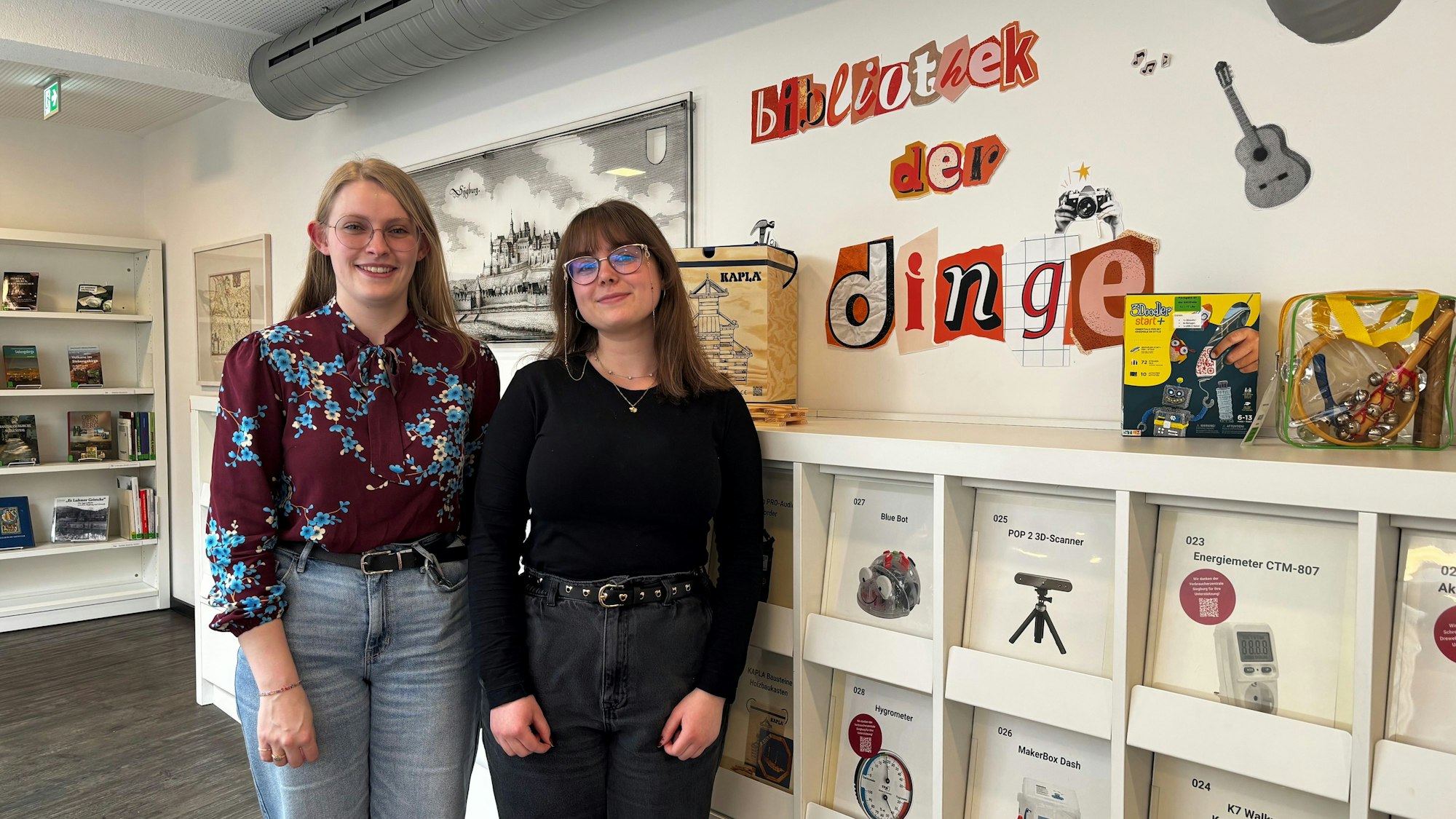 Zwei Frauen stehen vor dem Regal der Bibliothek der Dinge.