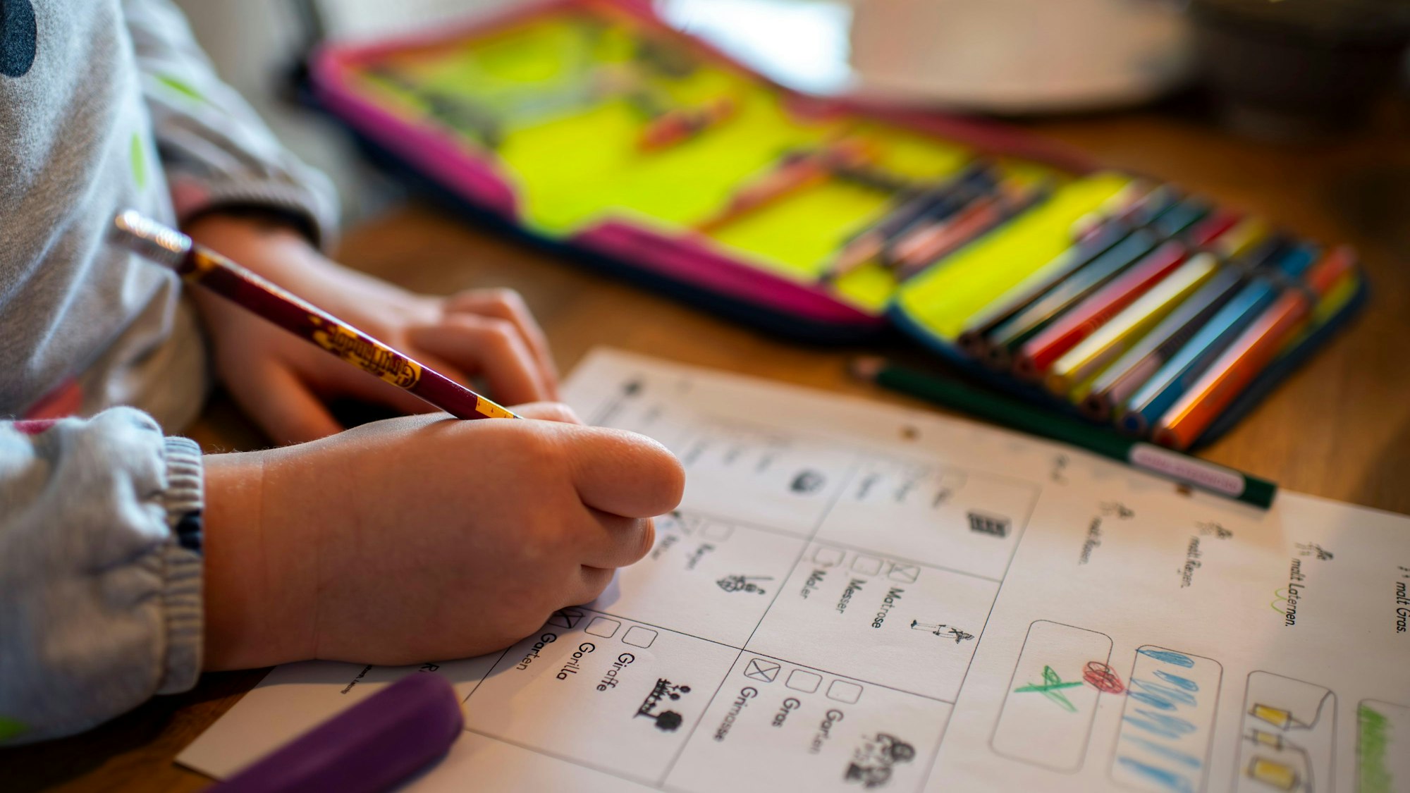 Ein Kind füllt ein Arbeitsblatt aus. Zu sehen ist nur die Hand, die den Stift führt.
