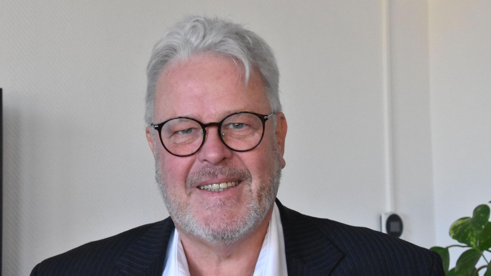 Ein Mann mit weißen Haaren und Bart, er trägt eine schwarze Brille.