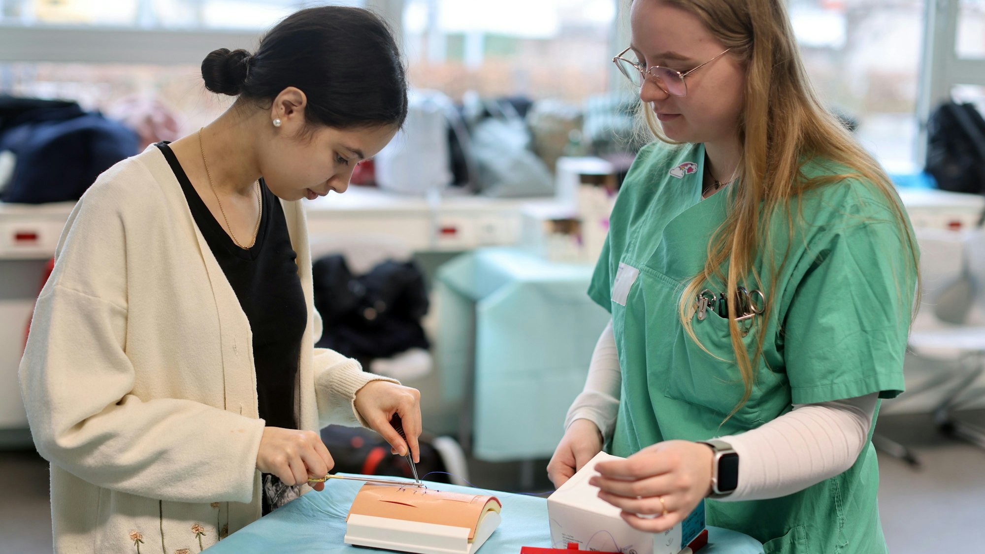 Schülerin Amina Gassa (l.) probiert in einem Workshop aus, wie Nähte gemacht werden. Geleitet wird er von Operationstechnischen Assistentinnen.