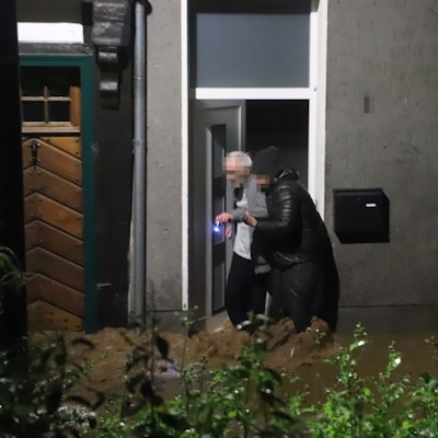Ein junger Mann hilft einem alten Mann aus dem Haus. Aufnahme aus der Flutnacht 14./15. Juli 2021.