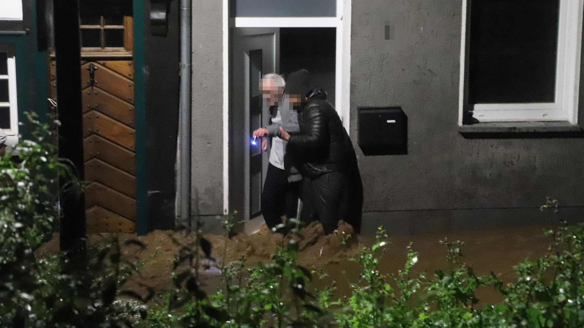 Ein junger Mann hilft einem alten Mann aus dem Haus. Aufnahme aus der Flutnacht 14./15. Juli 2021.