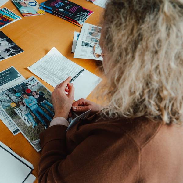 Das Foto zeigt eine Frau, die sich Printprodukte auf einem Tisch ansieht.