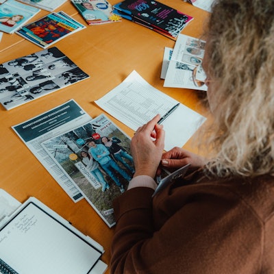 Das Foto zeigt eine Frau, die sich Printprodukte auf einem Tisch ansieht.