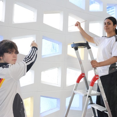 Zwei Jugendlich bemalen eine Wand.