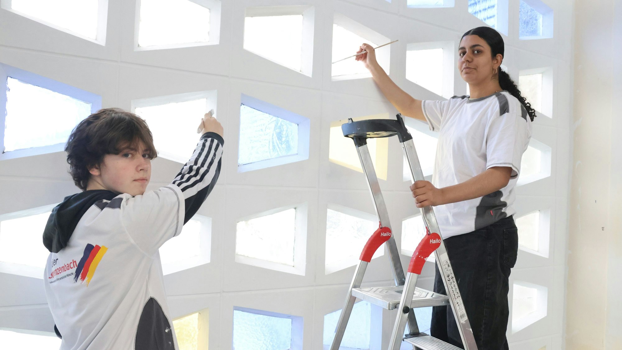 Zwei Jugendlich bemalen eine Wand.