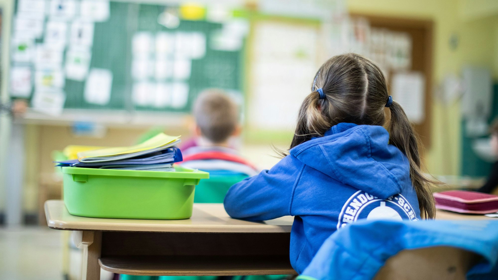 Eine Schülerin sitzt an einem Tisch und ist von hinten zu sehen.