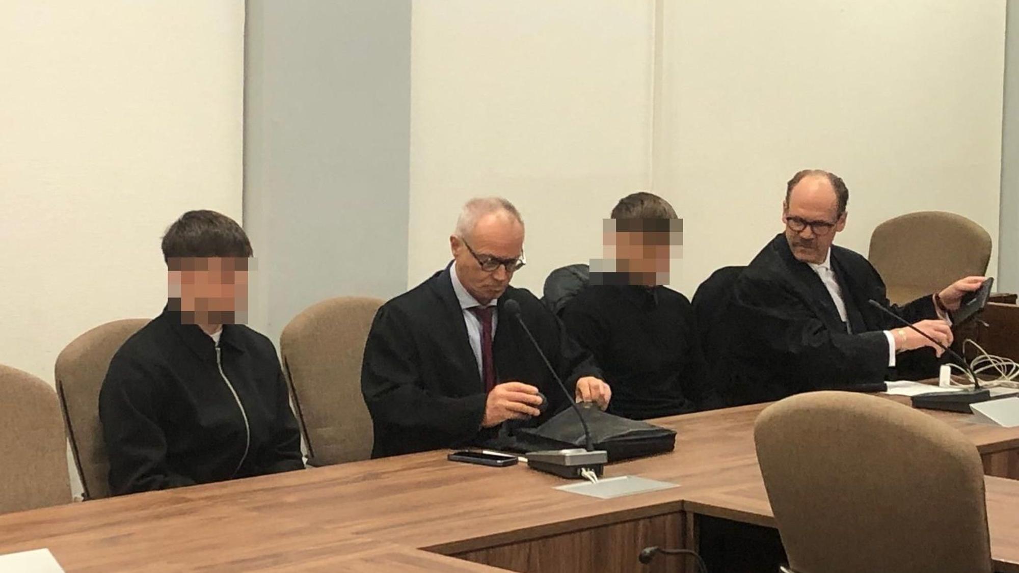 Das Foto zeigt zwei Anwälte mit ihren Anwälten, die unkenntlich gemacht wurden.