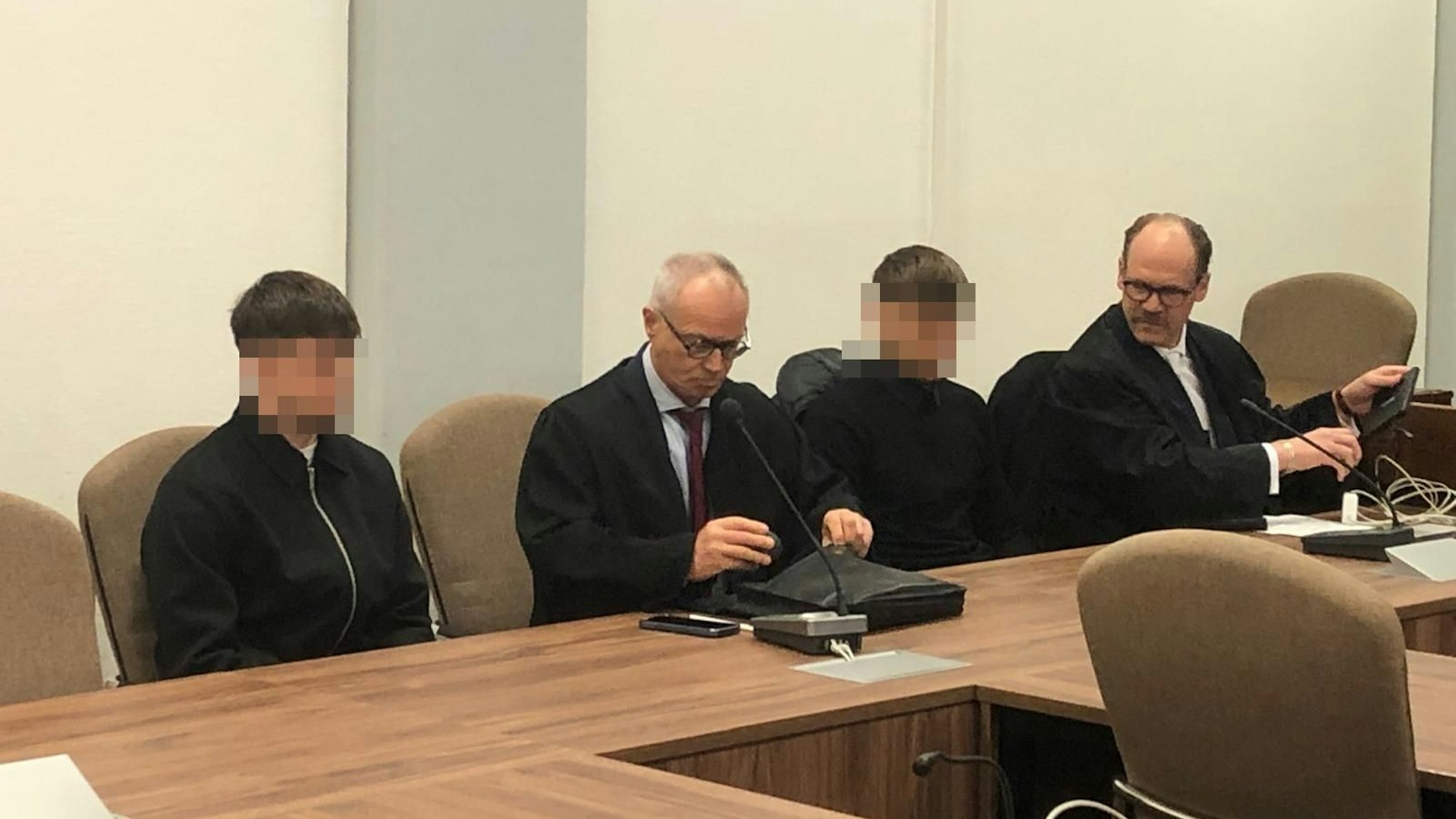 Das Bild zeigt die Angeklagten mit ihren Anwälten.