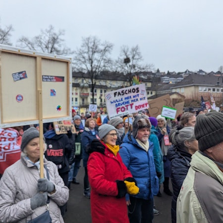 Menschen halten Protestplakate auf dem Overather Bahnhofplatz in die Höhe.