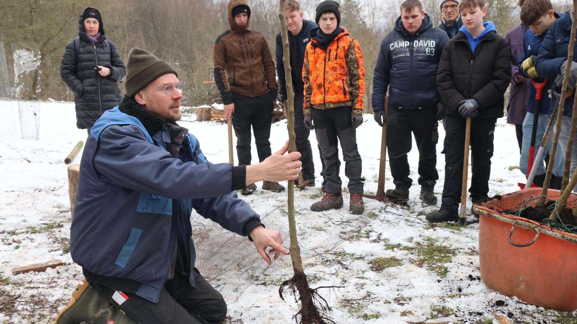 Der Engelskirchener Pädagoge Jens Herrmann gibt Tipps den Jugendlichen Tipps für das Einpflanzen der neuen Obstbäume. Diese stehen heute auf einer Wiese bei Bellingroth.
