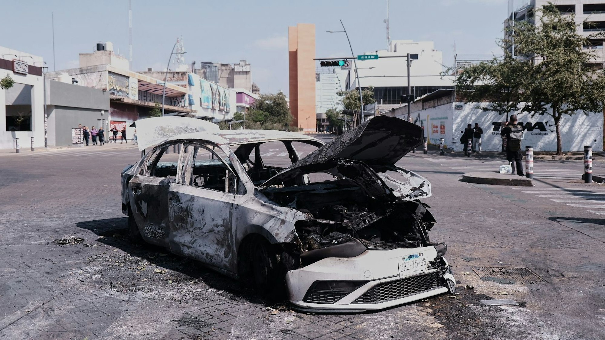 Ein Fahrzeug steht ausgebrannt am Straßenrand in Guadalajara im Bundesstaat Jalisco. Nach dem Tod von Mexikos mächtigstem Drogenboss wurden in mehreren Bundesstaaten Straßen mit brennenden Autos, Lastwagen und Bussen gesperrt.