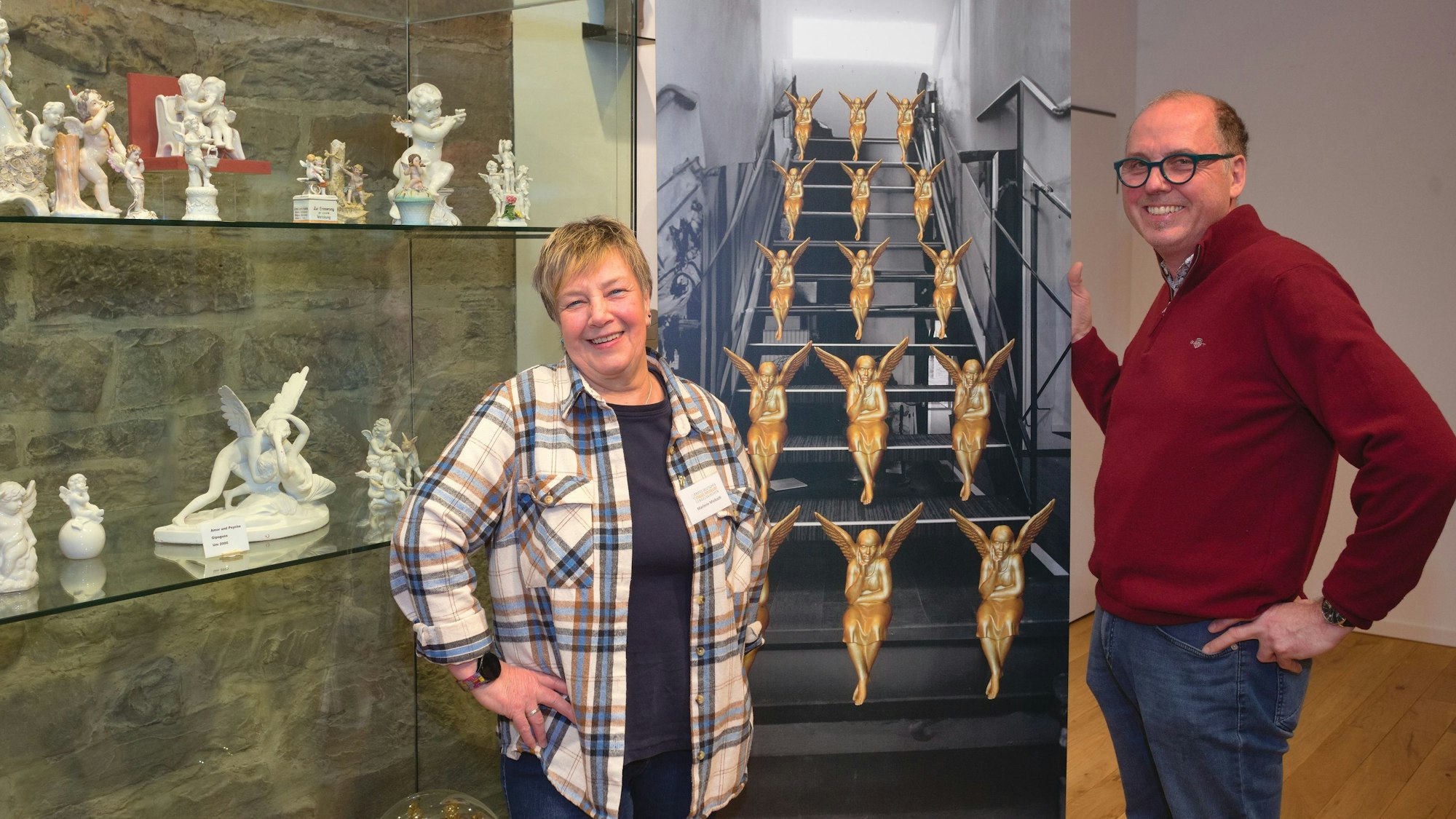 Eine Frau und ein Mann stehen vor Vitrinen mit Engelsfiguren.