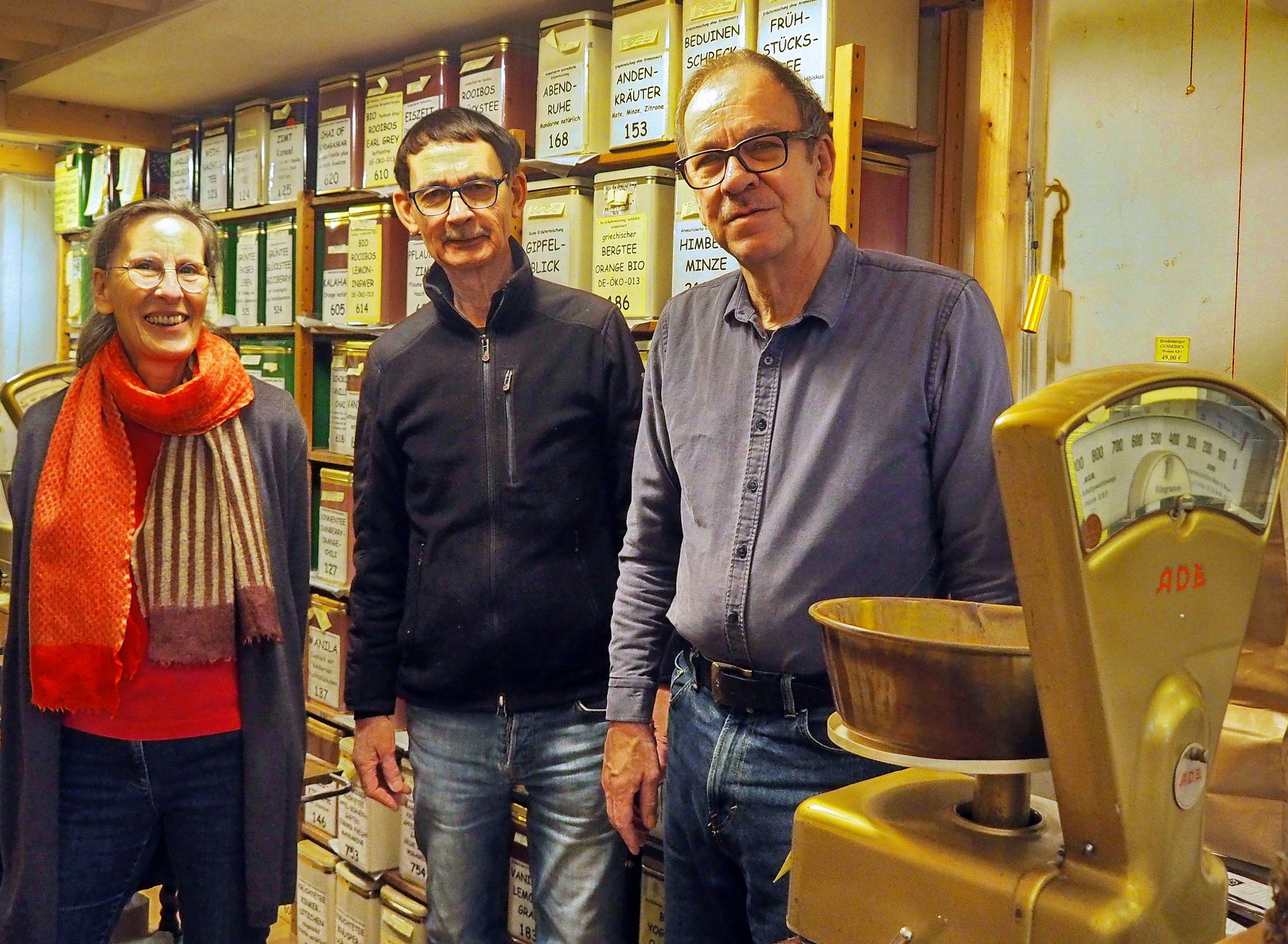 Eine Frau und zwei Männer stehen nebeneinander in einem Teegeschäft.