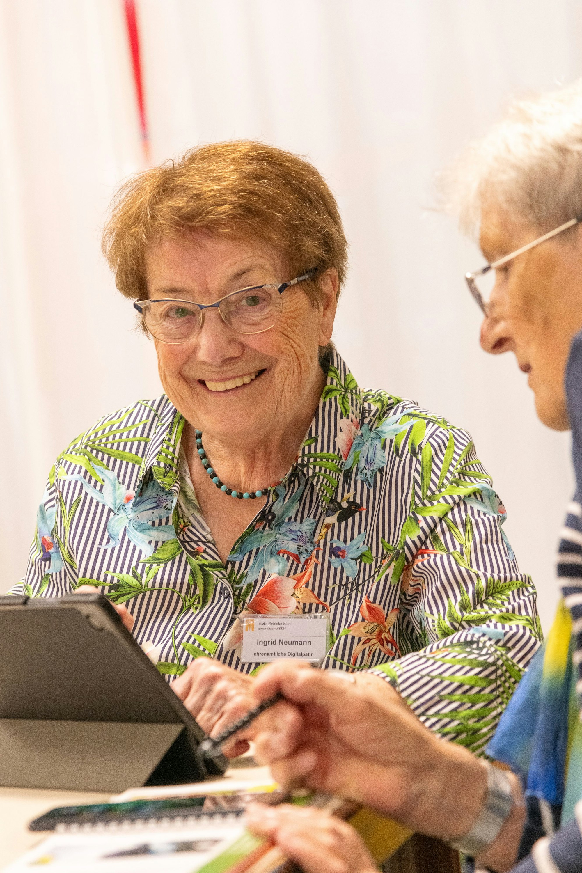 Eine ältere Frau sitzt lachend an einem Laptop.