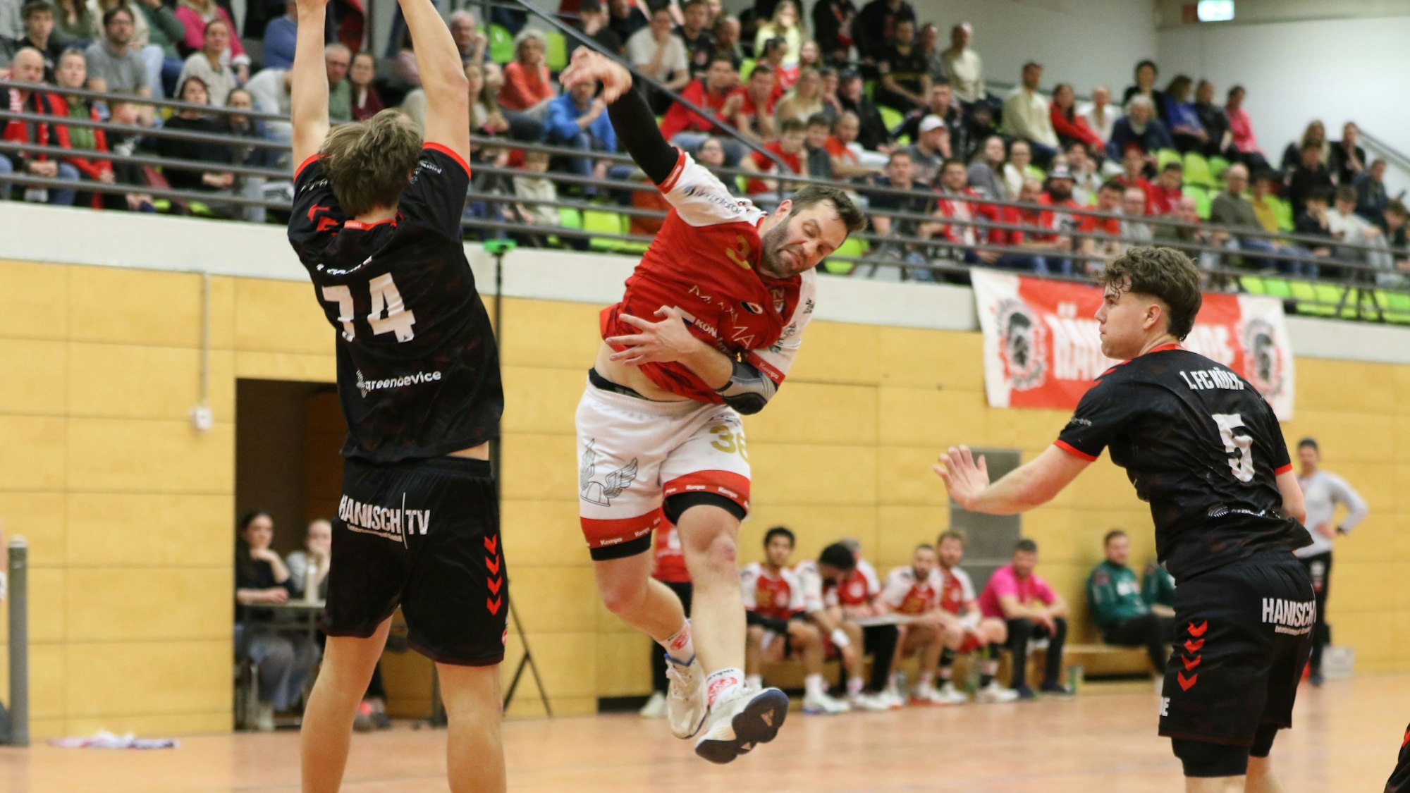 Daniel Schüller wendet seine ganze Kraft auf, um einen Ball zu werfen. Ein Gegenspieler macht sich vor ihm groß.