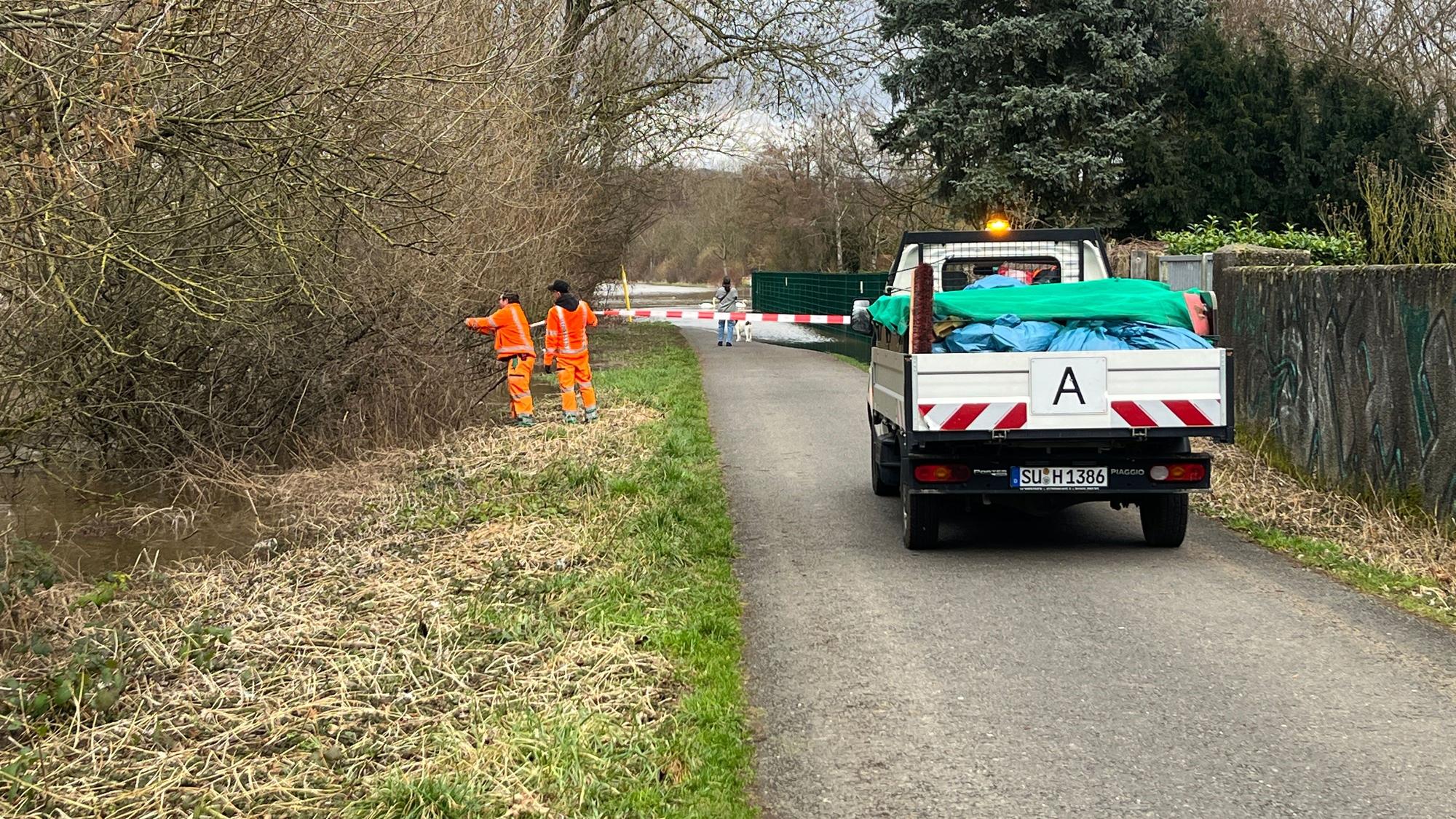 Städtische Mitarbeiter flatterten den Allner Weg ab, der in Teilen unter Wasser stand. Später wurde die Spundwand aufgebaut.