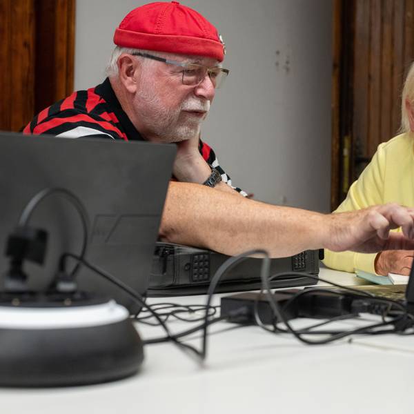 Ein Mann und eine Frau sitzen an einem Tisch, vor ihnen stehen Laptops.