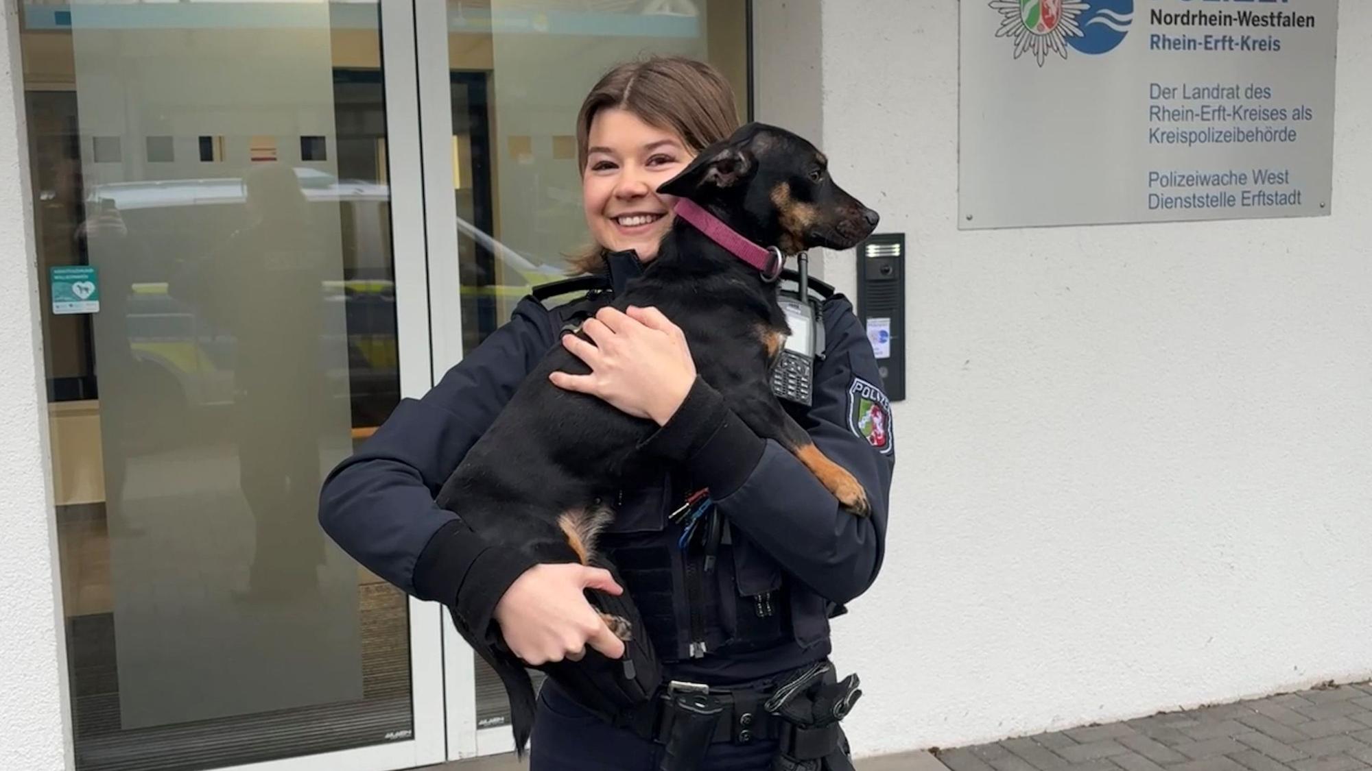 Eine Polizistin hält einen Hund auf dem Arm.