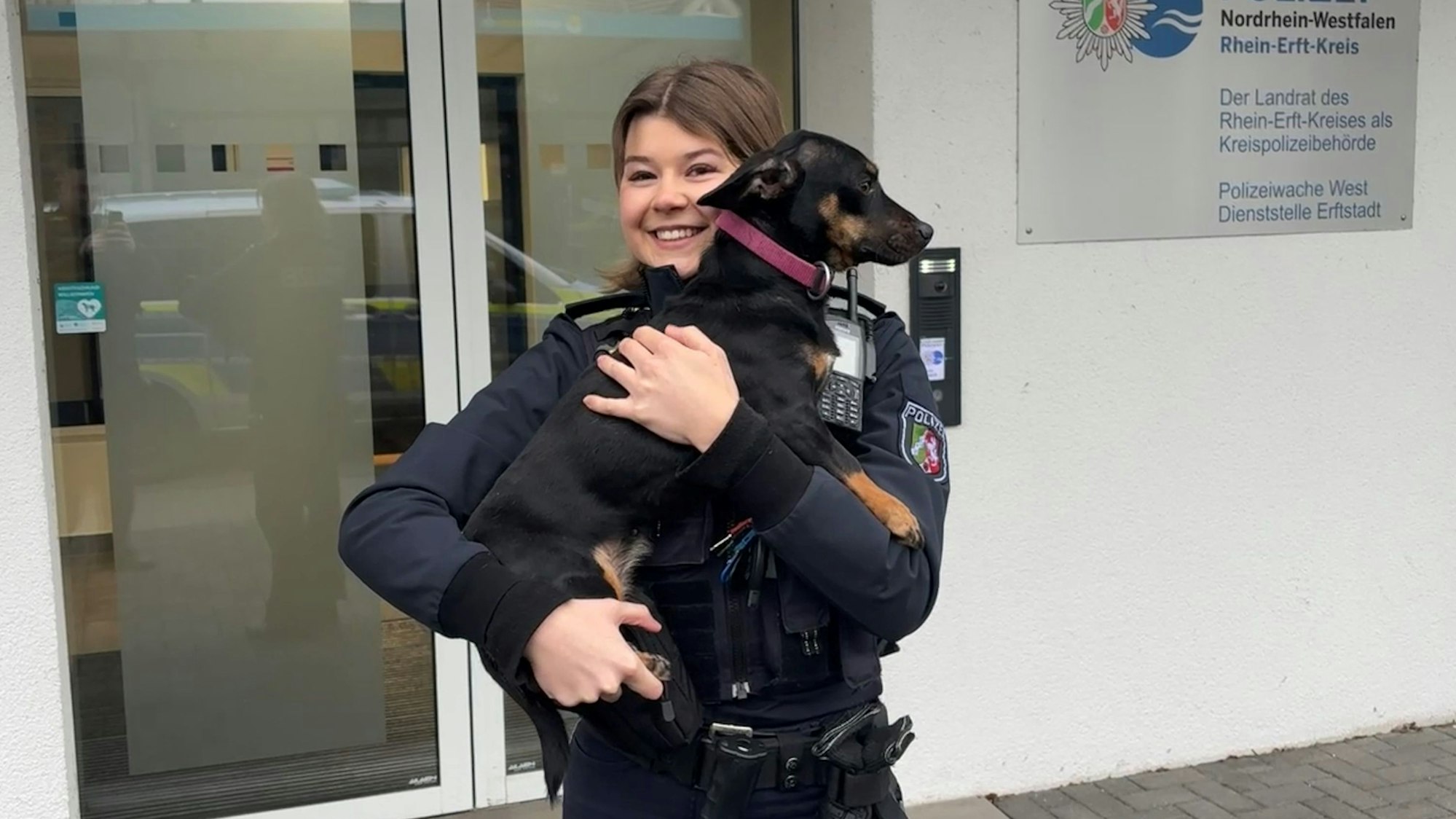 Eine Polizistin hält einen Hund auf dem Arm.