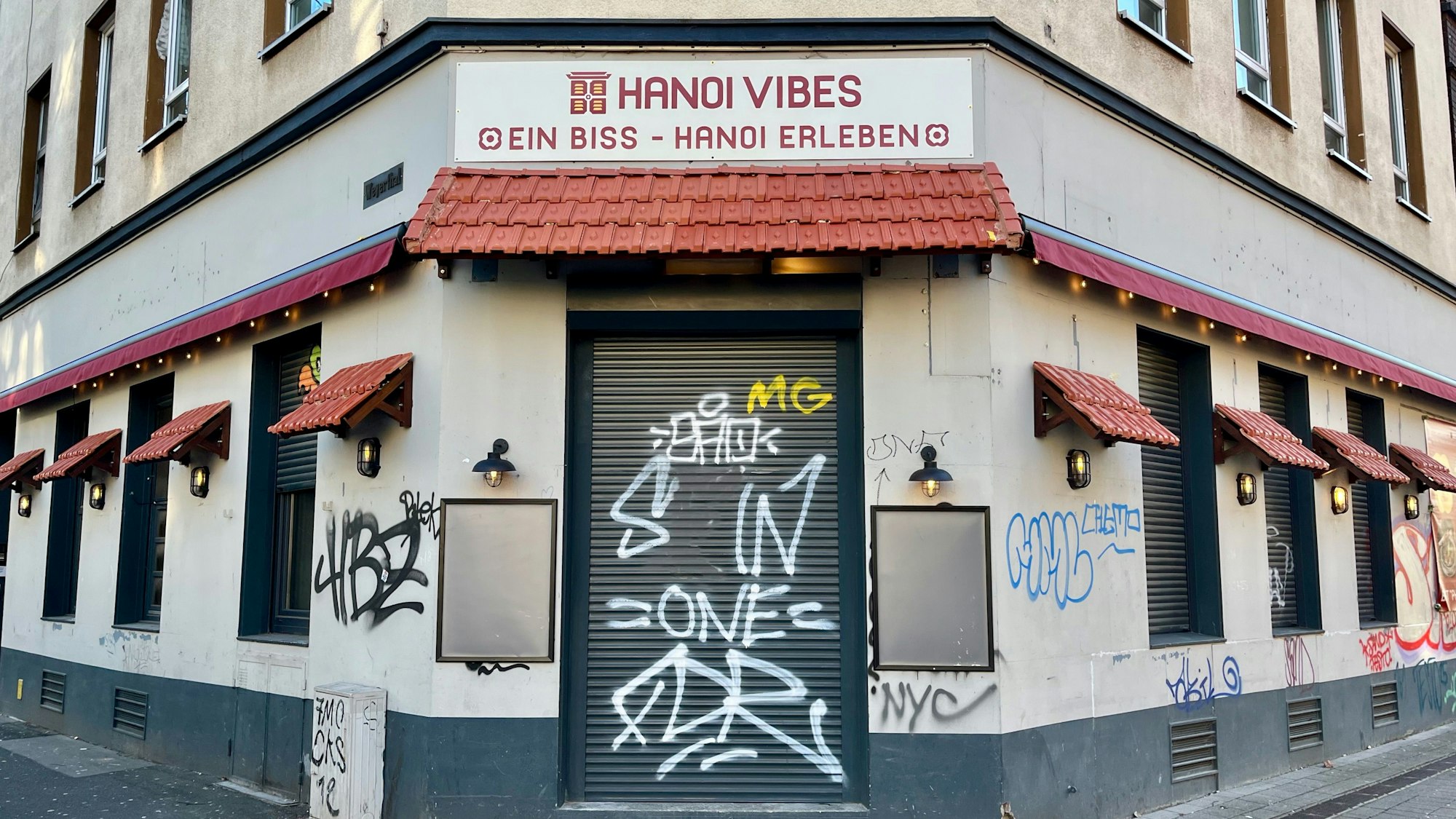 Blick auf ein Ecklokal in einem graffiti-besprühten Haus.