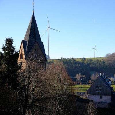 Blick von Kallmuth (im Vordergrund ist der Turm der Pfarrkirche zu sehen) auf den Ravelsberg, wo drei Windkraftanlagen stehen.