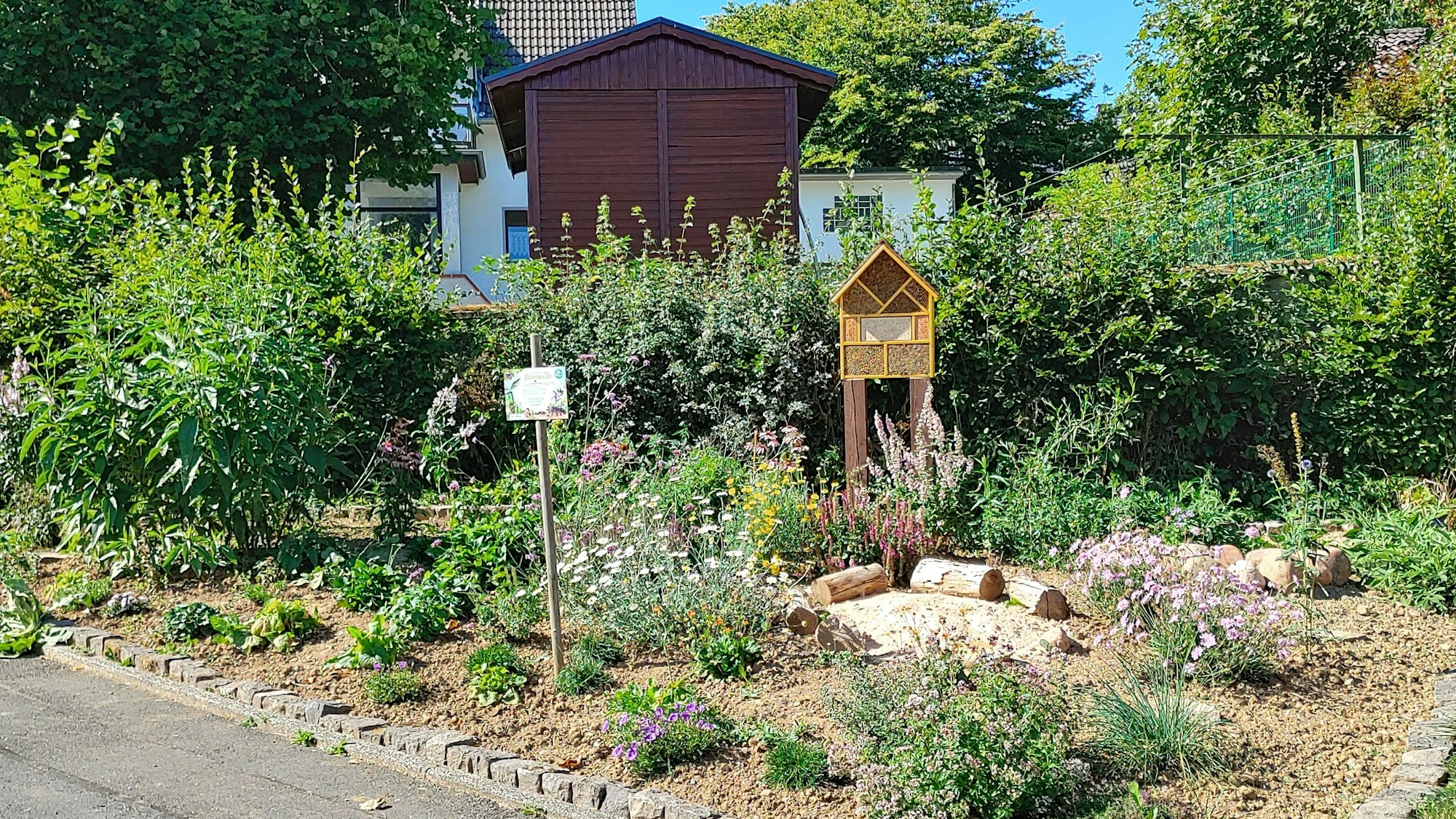 In einem Beet blühen unterschiedliche Stauden, ein Insektenhotel ist aufgestellt.