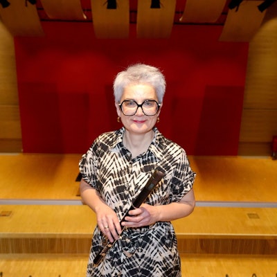 In einem Saal steht eine Frau mit Blockflöte.