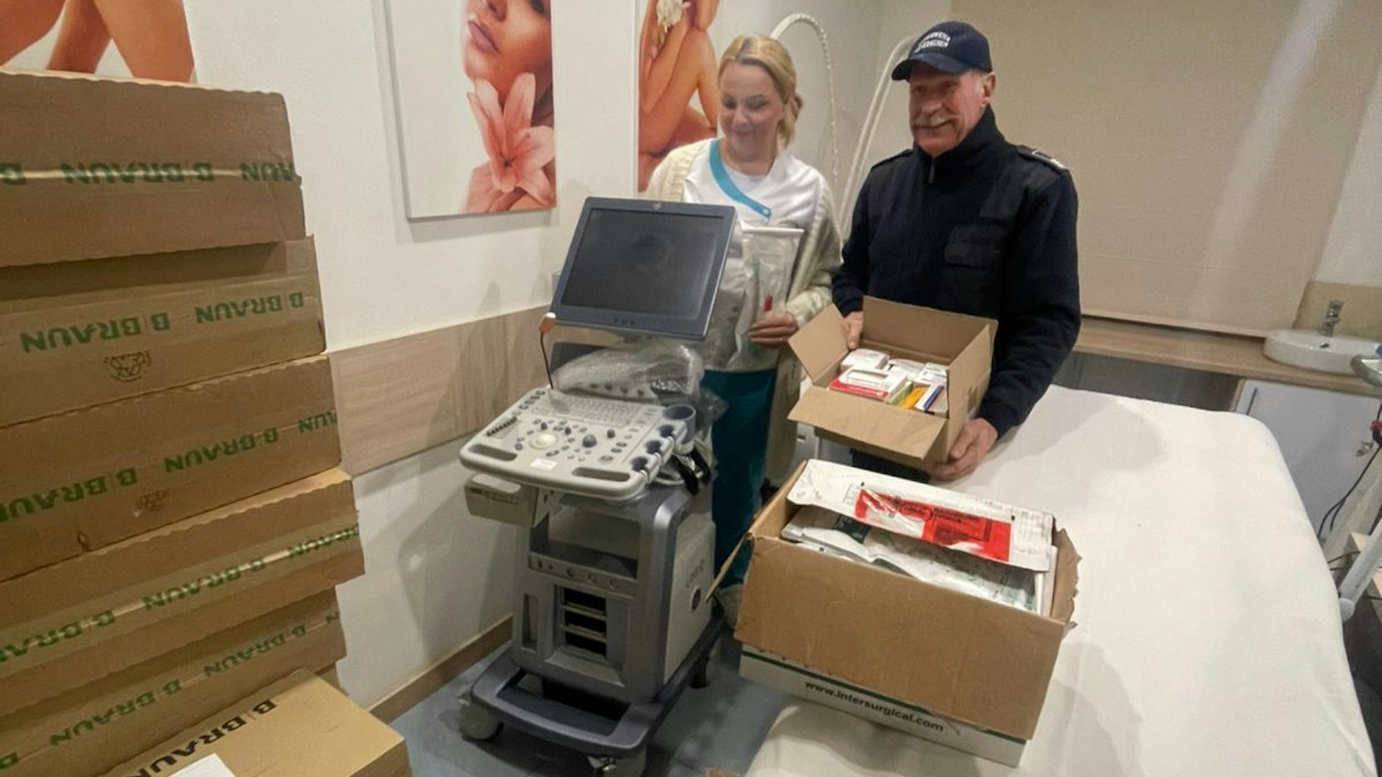 Gerd Kortschlag steht mit einer Klinikmitarbeiterin neben einem Ultraschallgerät.