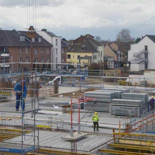 Auf der Baustelle eines großen Gebäudes sind Arbeiter unterwegs.