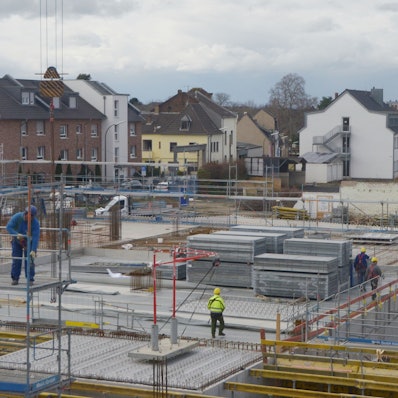 Auf der Baustelle eines großen Gebäudes sind Arbeiter unterwegs.
