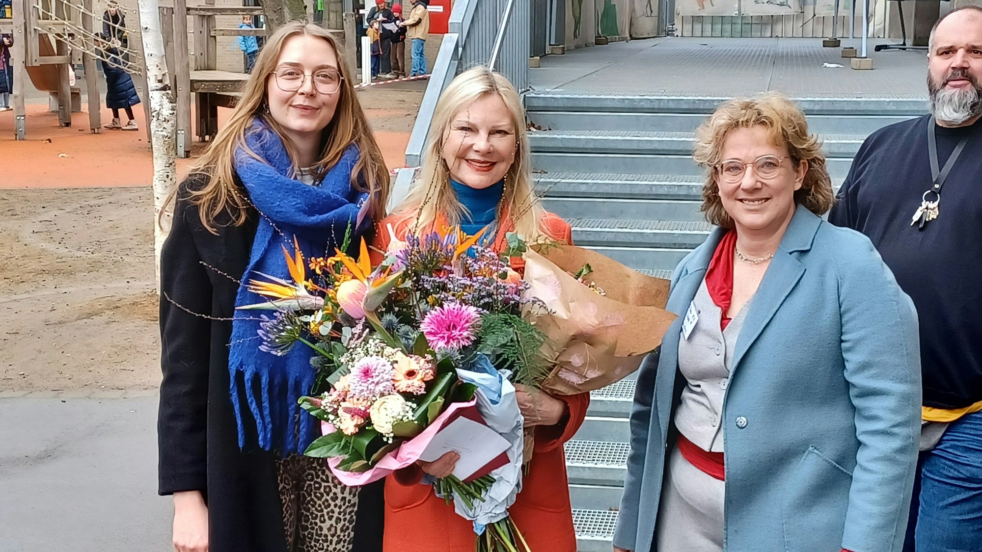 Drei Frauen stehen nebeneinander, die in der Mitte hält mehrere Blumensträuße.