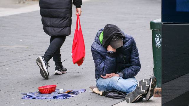 Ein Obdachloser sitzt auf der Straße.