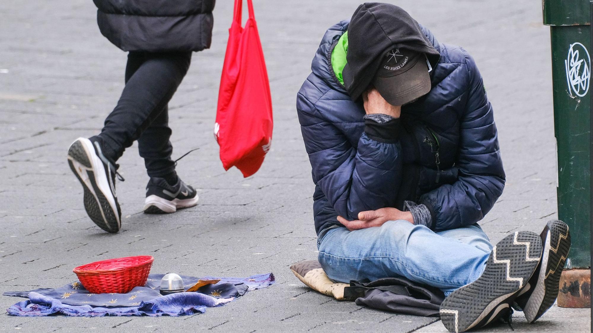 Ein Obdachloser sitzt auf der Straße.