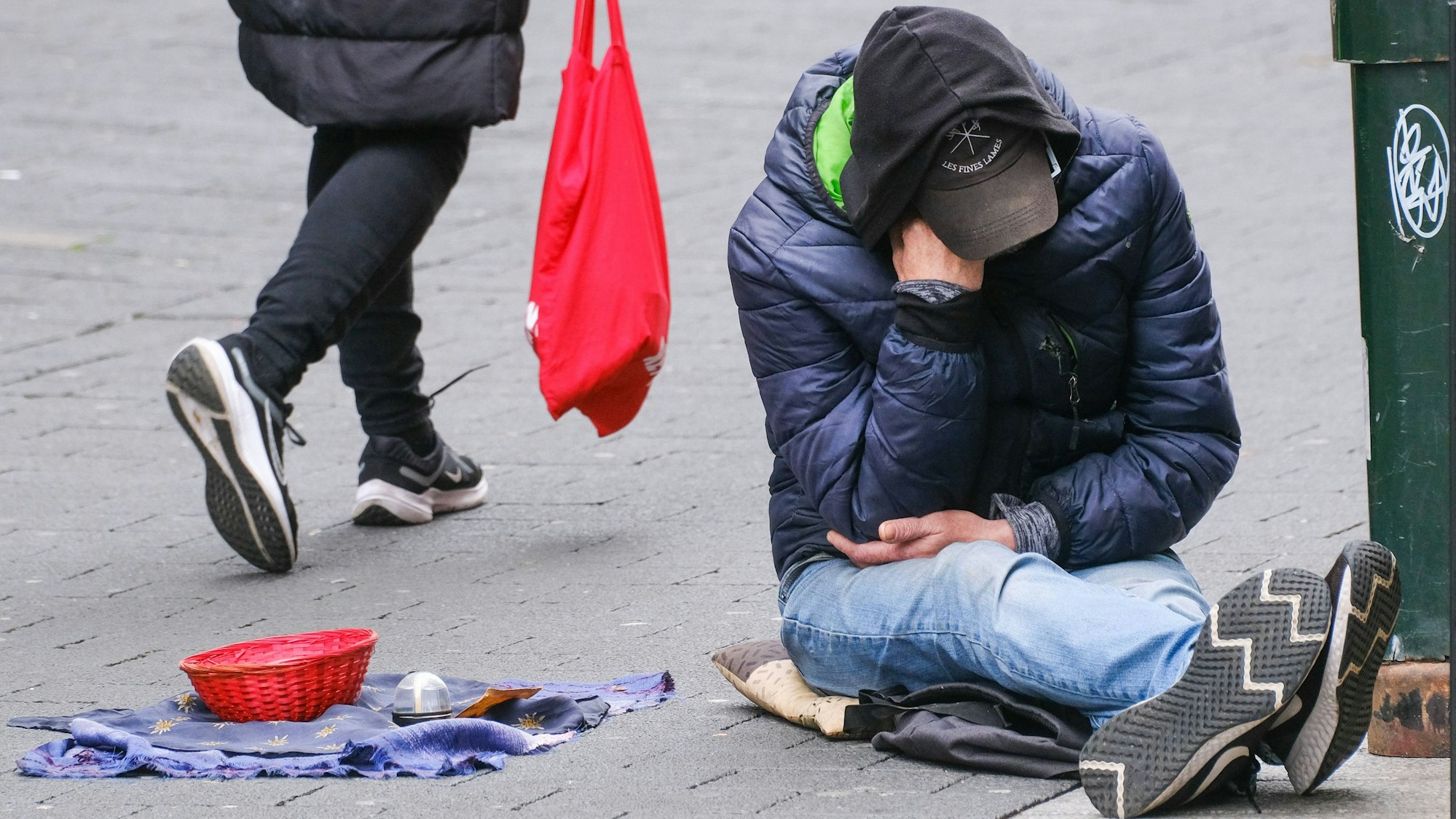 Ein Obdachloser sitzt auf der Straße.