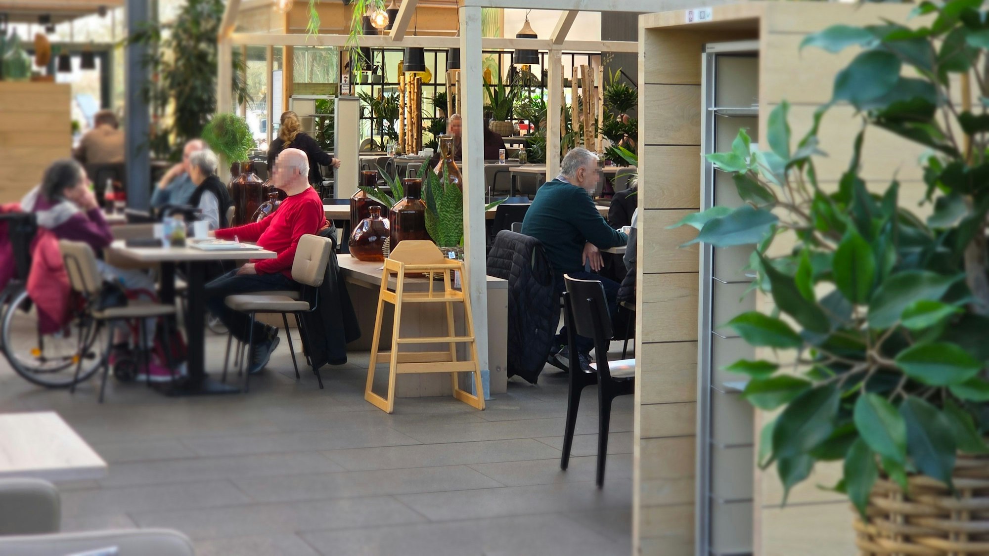 Der Gastraum in der Gartenküche liegt direkt im Gewächshaus und ist passend dekoriert mit viel Grün und Holzoptik.